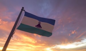 Lesotho Flag on Flagpole by Evening Sunset Sky